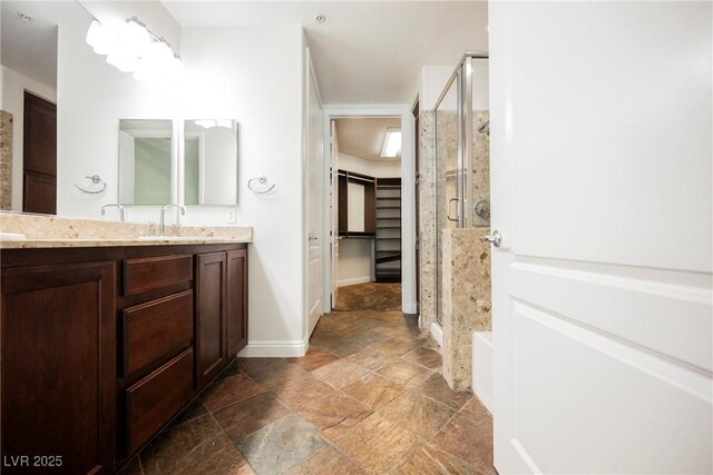 68 E Serene Ave Unit 224, Las Vegas, NV 89123 - bathroom with stone tile flooring, a shower stall, vanity, a spacious closet, and baseboards