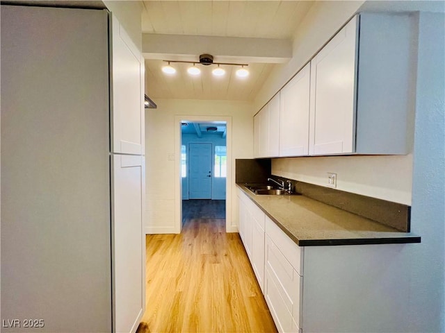 700 N Minnesota St, Las Vegas, NV 89107 - kitchen featuring a sink, white cabinetry, light wood-type flooring, beam ceiling, and dark countertops