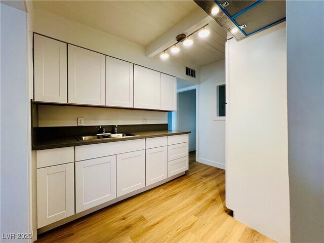 700 N Minnesota St, Las Vegas, NV 89107 - kitchen with a sink, dark countertops, light wood finished floors, white cabinetry, and track lighting