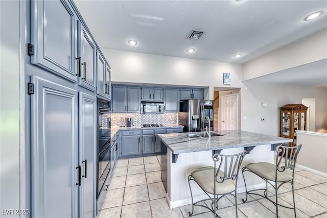 3050 Whispering Crest Dr, Henderson, NV 89052 - kitchen with black appliances, tasteful backsplash, light stone counters, a breakfast bar, and light tile patterned floors