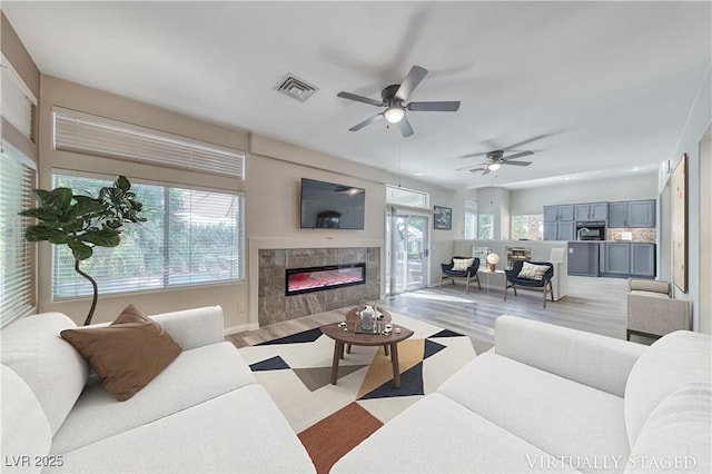 3050 Whispering Crest Dr, Henderson, NV 89052 - living room with a tiled fireplace, light wood finished floors, ceiling fan, and baseboards
