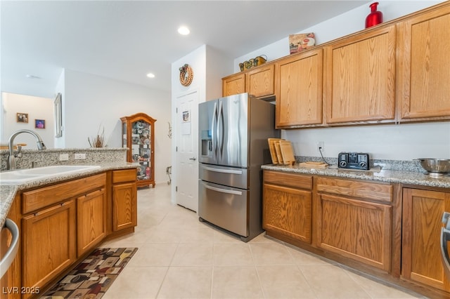 2413 Mourning Warbler Ave, North Las Vegas, NV 89084 - kitchen featuring stainless steel fridge, a sink, light tile patterned floors, brown cabinets, and recessed lighting