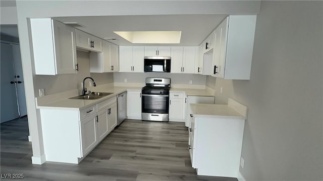 5720 Goldmount Ave, Las Vegas, NV 89107 - kitchen with stainless steel appliances, a sink, wood finished floors, and white cabinets