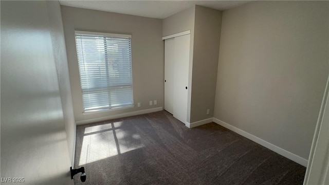 5720 Goldmount Ave, Las Vegas, NV 89107 - unfurnished bedroom with dark colored carpet, baseboards, and a closet