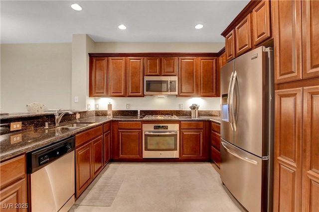 1560 Plaza Centre Dr Unit 103, Las Vegas, NV 89135 - kitchen featuring stainless steel appliances, a sink, dark stone countertops, recessed lighting, and brown cabinets