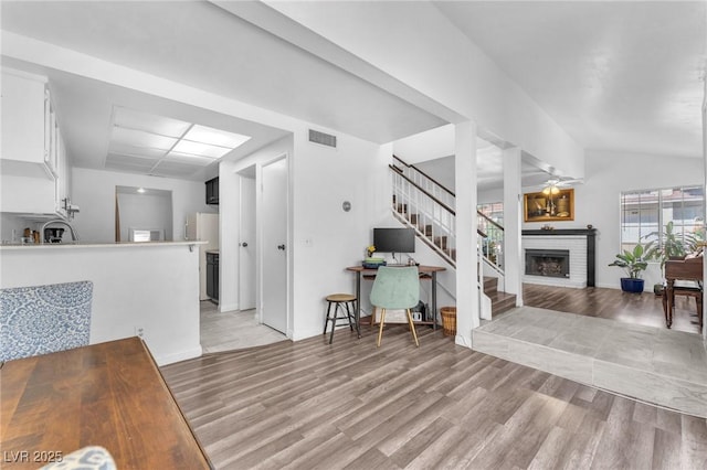 110 Huckleberry Ln, Henderson, NV 89074 - living room with light wood-style flooring, stairs, a fireplace, ceiling fan, and lofted ceiling
