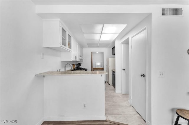 110 Huckleberry Ln, Henderson, NV 89074 - kitchen with freestanding refrigerator, a peninsula, white cabinetry, light countertops, and baseboards