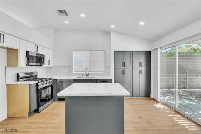 831 Purple Sage Ter, Henderson, NV 89015 - kitchen with appliances with stainless steel finishes, a sink, lofted ceiling, light wood-style flooring, and gray cabinetry