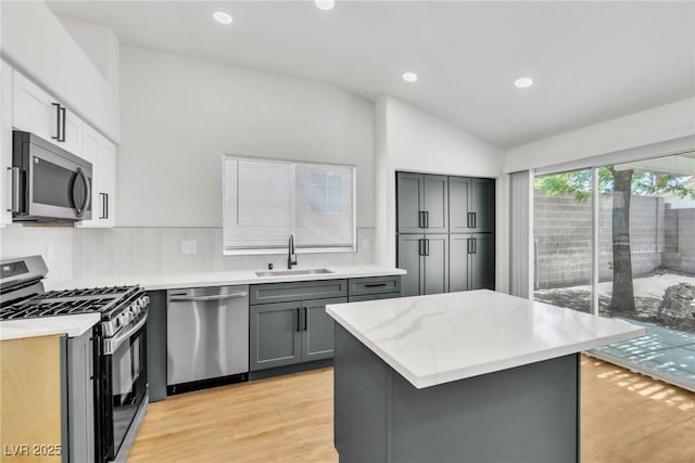 831 Purple Sage Ter, Henderson, NV 89015 - kitchen featuring stainless steel appliances, a sink, vaulted ceiling, gray cabinets, and light wood finished floors