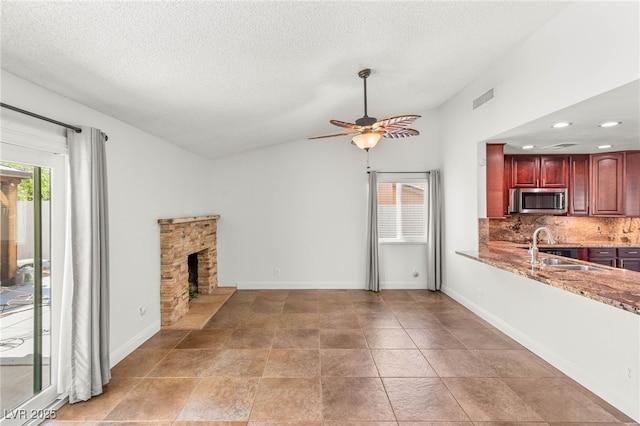 1505 Irene Dr, Boulder City, NV 89005 - unfurnished living room with a sink, vaulted ceiling, ceiling fan, recessed lighting, and a stone fireplace
