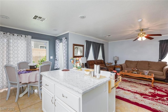 3404 Brayton Mist Dr, North Las Vegas, NV 89081 - kitchen featuring light tile patterned floors, white cabinets, ornamental molding, ceiling fan, and a center island