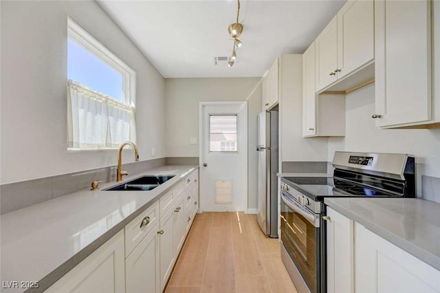 524 Hopi Pl, Boulder City, NV 89005 - kitchen with stainless steel appliances, a sink, white cabinetry, light countertops, and light wood-style floors