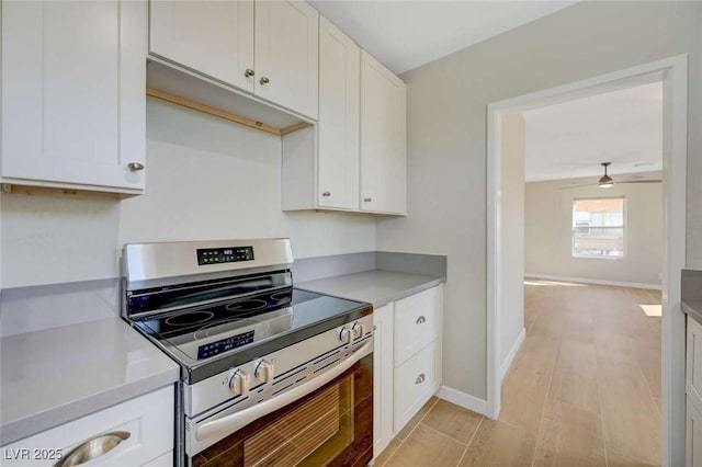 524 Hopi Pl, Boulder City, NV 89005 - kitchen with electric stove, light countertops, white cabinets, light wood-type flooring, and a ceiling fan