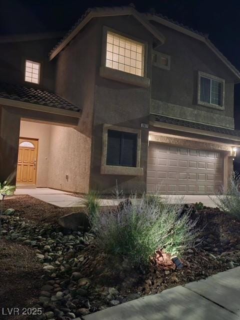 2077 Alki Beach Ave, Laughlin, NV 89029 - property exterior at night with a garage, stucco siding, and a tiled roof