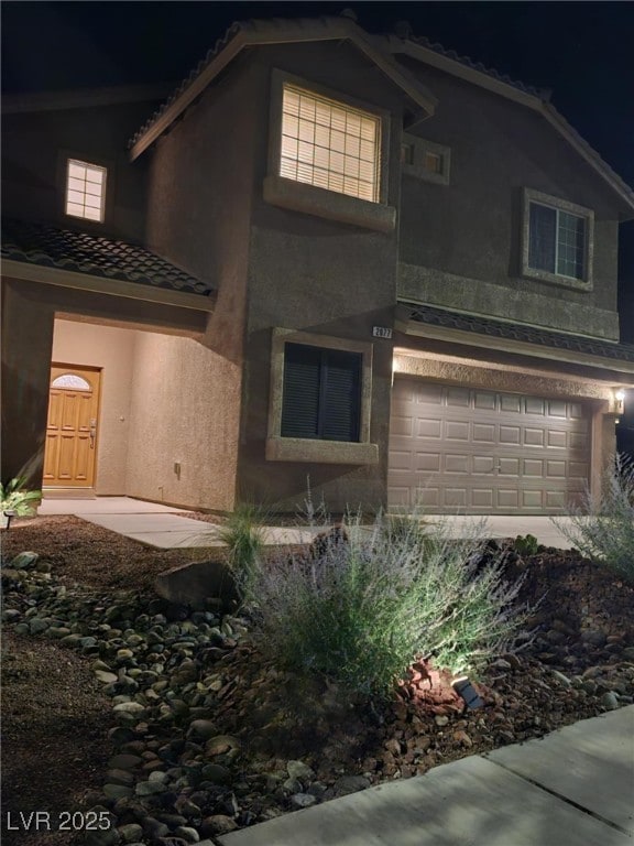 2077 Alki Beach Ave, Laughlin, NV 89029 - property exterior at night with stucco siding, a garage, and a tile roof