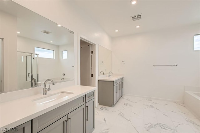 6830 Fallen Rock St, North Las Vegas, NV 89084 - full bath featuring two vanities, a bath, a stall shower, recessed lighting, and marble look tiles