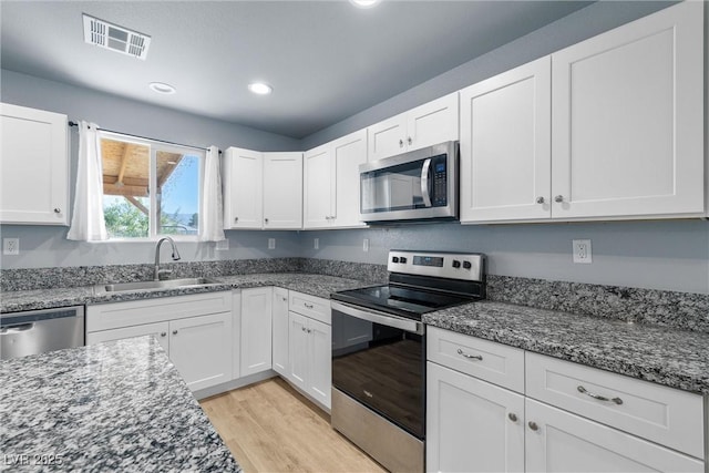 100 Eton St, Pahrump, NV 89048 - kitchen featuring stainless steel appliances, white cabinetry, dark stone counters, light wood-style floors, and recessed lighting