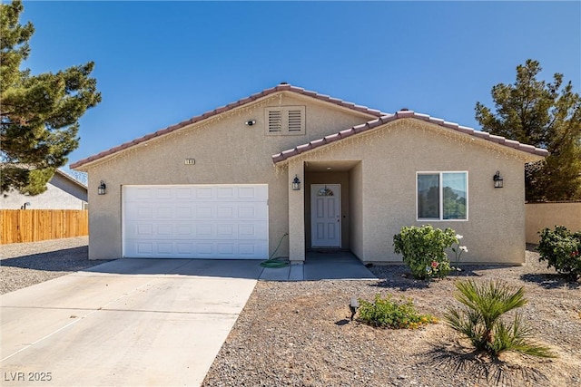 100 Eton St, Pahrump, NV 89048 - mediterranean / spanish house with stucco siding, an attached garage, driveway, and a tiled roof