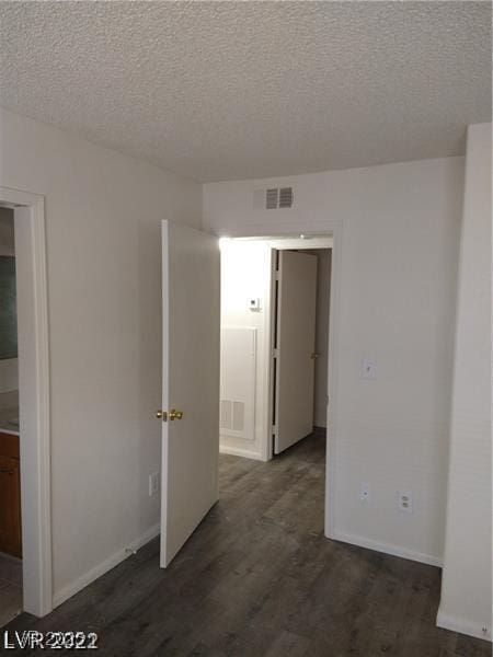 1608 N Torrey Pines Dr Unit 103, Las Vegas, NV 89108 - empty room with dark wood-style floors, a textured ceiling, and baseboards