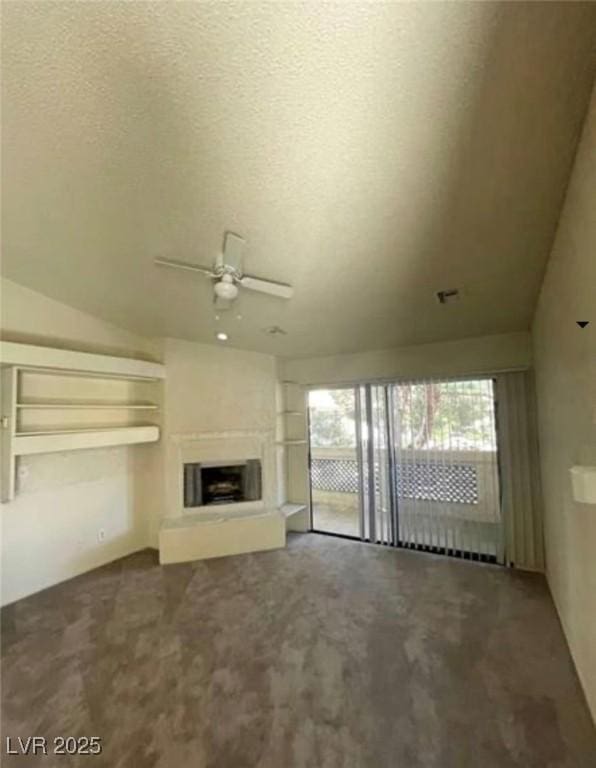 2995 E Sunset Rd Unit 237, Las Vegas, NV 89120 - unfurnished living room with ceiling fan, carpet floors, a fireplace with raised hearth, vaulted ceiling, and a textured ceiling