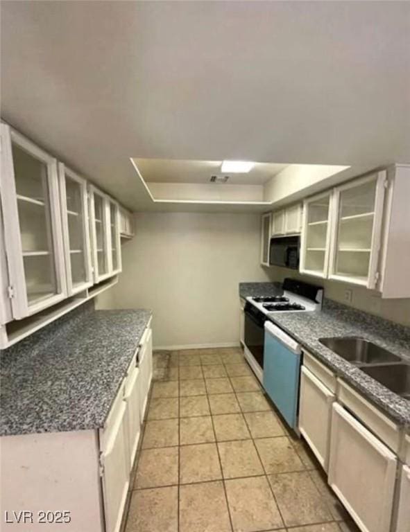 2995 E Sunset Rd Unit 237, Las Vegas, NV 89120 - kitchen featuring dishwasher, a tray ceiling, baseboards, and glass insert cabinets