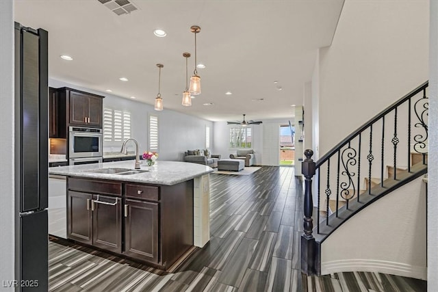 3096 Beaux Art Ave, Henderson, NV 89044 - kitchen featuring stainless steel oven, a sink, dark brown cabinetry, healthy amount of natural light, and recessed lighting