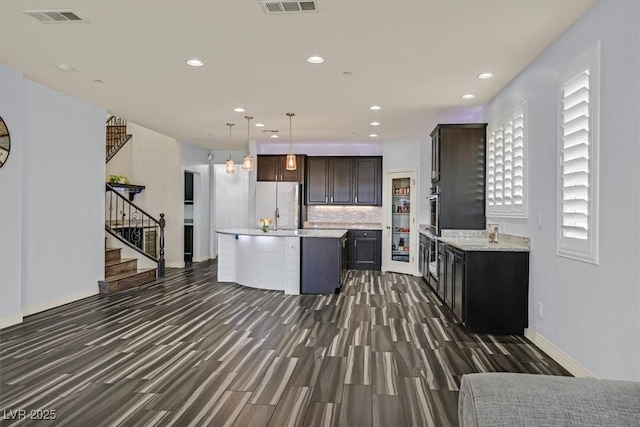 3096 Beaux Art Ave, Henderson, NV 89044 - kitchen with dark wood finished floors, freestanding refrigerator, dark brown cabinets, a kitchen island with sink, and tasteful backsplash
