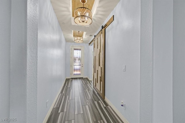 3096 Beaux Art Ave, Henderson, NV 89044 - corridor with a chandelier, a barn door, baseboards, and wood finished floors