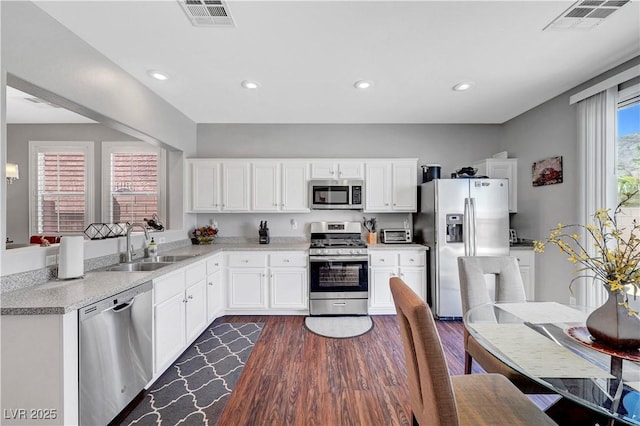 4020 Driscoll Mountain St, Las Vegas, NV 89129 - kitchen with stainless steel appliances, dark wood finished floors, a sink, white cabinetry, and recessed lighting