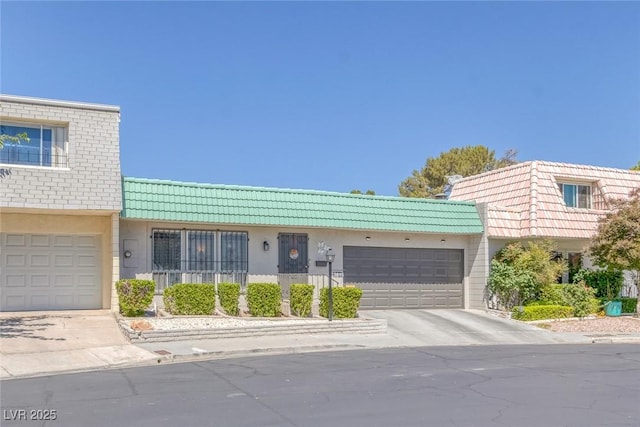 3815 Atlantis St, Las Vegas, NV 89121 - townhome / multi-family property featuring driveway, a tiled roof, stucco siding, an attached garage, and mansard roof