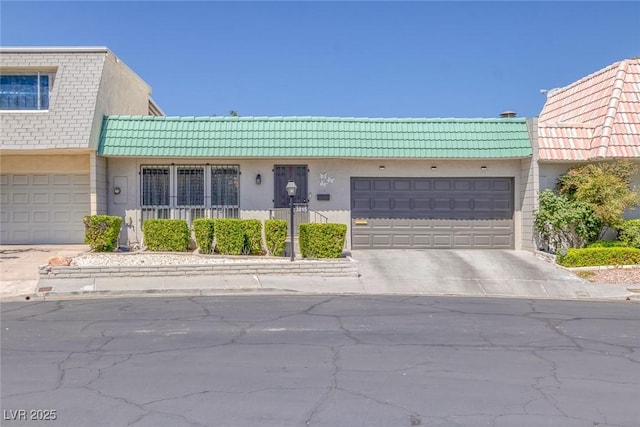 3815 Atlantis St, Las Vegas, NV 89121 - view of property featuring concrete driveway, stucco siding, an attached garage, and a tile roof