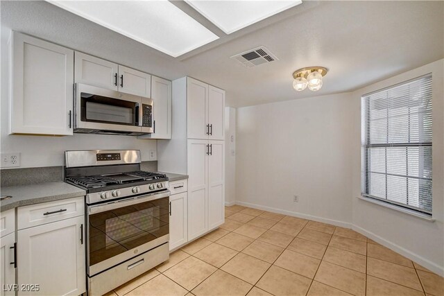 6521 Faith Peak Dr, Las Vegas, NV 89108 - kitchen with stainless steel appliances, white cabinetry, light tile patterned floors, and baseboards
