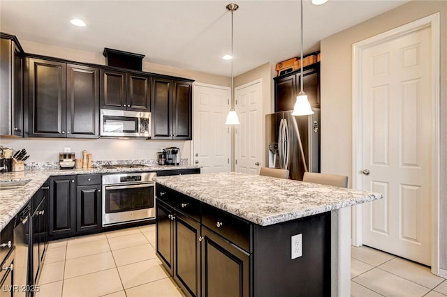 9846 Sunriver Meadows Ave, Las Vegas, NV 89148 - kitchen with stainless steel appliances, light tile patterned floors, a center island, pendant lighting, and light stone counters