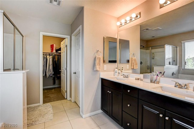 9846 Sunriver Meadows Ave, Las Vegas, NV 89148 - bathroom featuring a stall shower, double vanity, a spacious closet, tile patterned floors, and baseboards