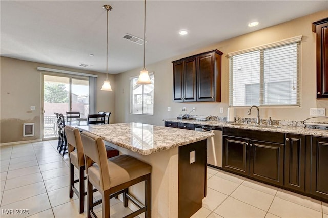 9846 Sunriver Meadows Ave, Las Vegas, NV 89148 - kitchen featuring stainless steel dishwasher, a sink, light tile patterned floors, a kitchen island, and a kitchen bar