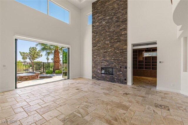 2436 Grassy Spring Pl, Las Vegas, NV 89135 - unfurnished living room with a towering ceiling, stone tile flooring, and a stone fireplace