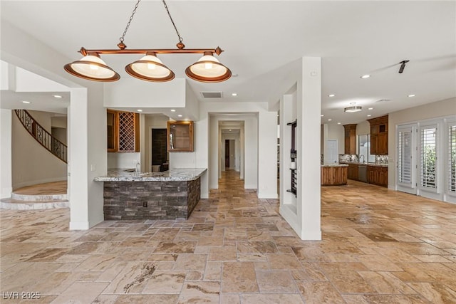 2436 Grassy Spring Pl, Las Vegas, NV 89135 - kitchen with stone tile floors, brown cabinetry, glass insert cabinets, recessed lighting, and light stone counters