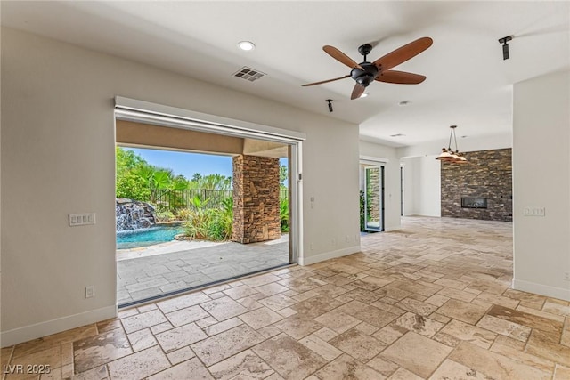 2436 Grassy Spring Pl, Las Vegas, NV 89135 - unfurnished living room featuring a ceiling fan, stone tile floors, a stone fireplace, and recessed lighting