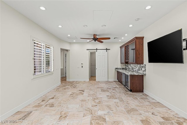 2436 Grassy Spring Pl, Las Vegas, NV 89135 - unfurnished living room with a barn door, recessed lighting, ceiling fan, attic access, and light stone finish flooring