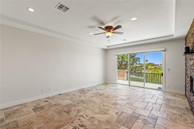 2436 Grassy Spring Pl, Las Vegas, NV 89135 - empty room with a stone fireplace, a ceiling fan, stone tile flooring, recessed lighting, and a raised ceiling