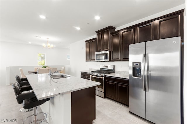 2495 Sunflower Days Ave Unit 2052, North Las Vegas, NV 89031 - kitchen with appliances with stainless steel finishes, a sink, a kitchen island with sink, a chandelier, and light stone counters