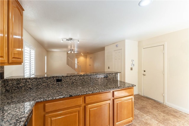 7923 Homer Ct, Las Vegas, NV 89139 - kitchen with dark stone counters, a peninsula, and baseboards