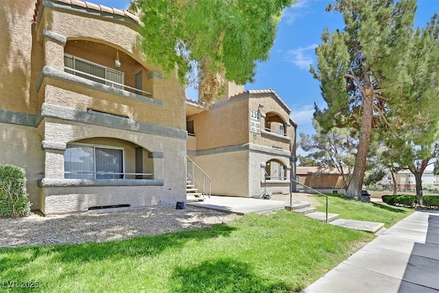 230 Mission Newport Ln Unit 104, Las Vegas, NV 89107 - view of front of property with a balcony, stucco siding, a tile roof, and a front lawn