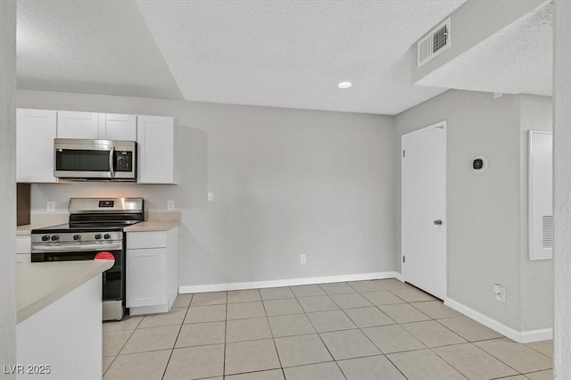 230 Mission Newport Ln Unit 104, Las Vegas, NV 89107 - kitchen with appliances with stainless steel finishes, white cabinetry, light countertops, baseboards, and a textured ceiling