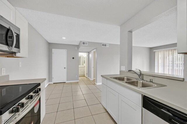 230 Mission Newport Ln Unit 104, Las Vegas, NV 89107 - kitchen featuring appliances with stainless steel finishes, a textured ceiling, white cabinetry, light tile patterned floors, and a sink