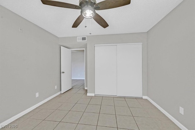 230 Mission Newport Ln Unit 104, Las Vegas, NV 89107 - unfurnished bedroom featuring light tile patterned floors, baseboards, a closet, a ceiling fan, and a textured ceiling
