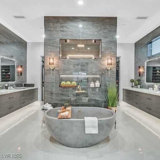 5400 Mello Ave, Las Vegas, NV 89131 - bathroom featuring a freestanding bath, marble tiled flooring, two vanities, tile walls, and recessed lighting