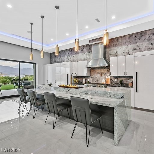 5400 Mello Ave, Las Vegas, NV 89131 - kitchen featuring modern cabinets, wall chimney range hood, white cabinetry, a towering ceiling, and light marble finish floors