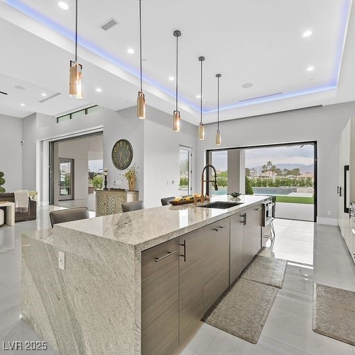 5400 Mello Ave, Las Vegas, NV 89131 - kitchen with modern cabinets, a tray ceiling, recessed lighting, a large island, and light stone countertops