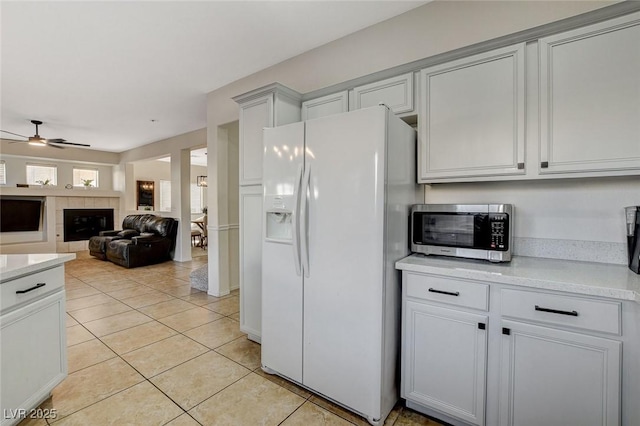 10988 Salernes St, Las Vegas, NV 89141 - kitchen with white fridge with ice dispenser, stainless steel microwave, a ceiling fan, and light countertops